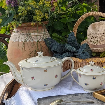 Elefántcsontszínű, virágokkal díszített porcelán teáskanna és cukortartó