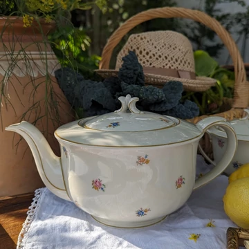 Elefántcsontszínű, virágokkal díszített porcelán teáskanna és cukortartó