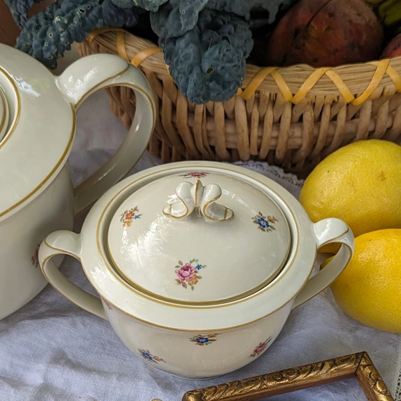 Elefántcsontszínű, virágokkal díszített porcelán teáskanna és cukortartó
