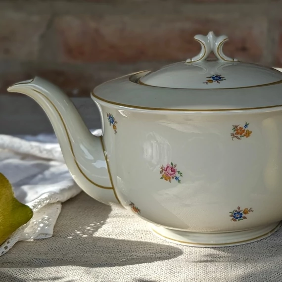 Elefántcsontszínű, virágokkal díszített porcelán teáskanna és cukortartó