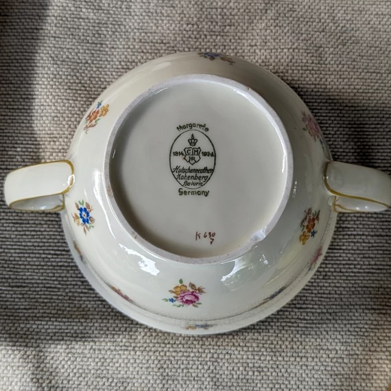 Elefántcsontszínű, virágokkal díszített porcelán teáskanna és cukortartó