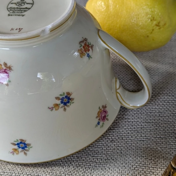 Elefántcsontszínű, virágokkal díszített porcelán teáskanna és cukortartó