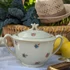 Elefántcsontszínű, virágokkal díszített porcelán teáskanna és cukortartó