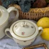Elefántcsontszínű, virágokkal díszített porcelán teáskanna és cukortartó