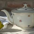 Elefántcsontszínű, virágokkal díszített porcelán teáskanna és cukortartó
