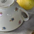 Elefántcsontszínű, virágokkal díszített porcelán teáskanna és cukortartó